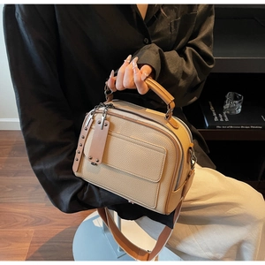 Detail of beige lychee grain leather crossbody bag with wide strap and dual zippers