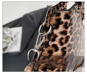Detail of silver metal hook clasp on leopard print bucket bag with glossy texture