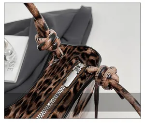 Detail shot of the smooth metal zipper closure and knotted leopard print handle