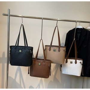 Detail view of woven tote bags in four colors with gold buckles and leather straps