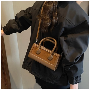 Brown vintage square bag with circular buckles and mixed texture worn by a model