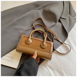 Detail view of brown textured leather shoulder bag with stitching and crossbody strap