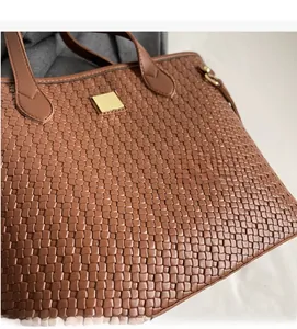 Detailed view of woven brown tote bag with leather texture and square gold metal plate
