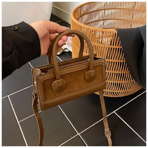 Detail of dark brown leather handbag with two circular accents and crossbody strap