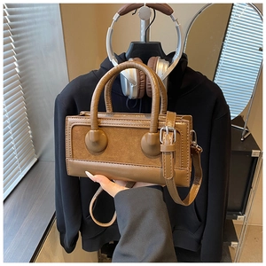 Detail of a brown leather crossbody bag featuring textured suede panels and silver hardware