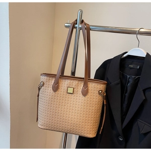 Close-up of retro woven tote bag texture with brown leather strap on metal hanger