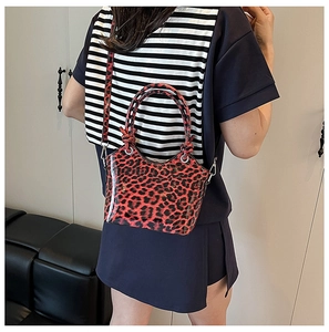 Side view of red leopard print crossbody bag with glossy finish and silver buckles