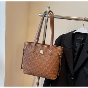 Detailed close-up of brown woven tote bag texture with golden buckle and tassel detail
