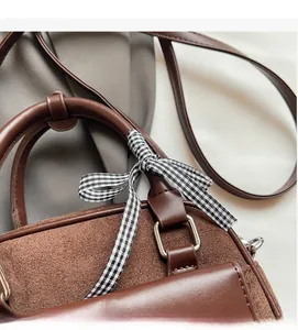 Détail du sac bowling marron avec nœud à carreaux et ferrures métalliques argentées