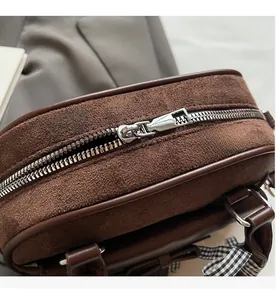 Detalle de la cremallera metálica en el bolso estilo bowling de ante marrón
