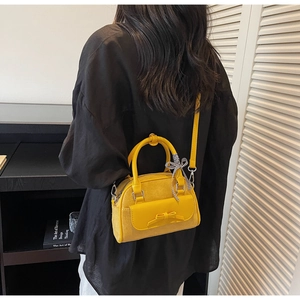 Mannequin portant un sac Boston jaune vif avec empiècements en daim et détail nœud élégant