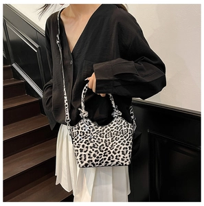 Detail of leopard print handbag featuring a knotted handle and adjustable crossbody strap
