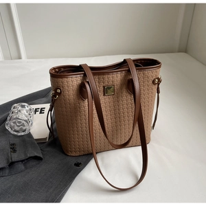 Detailed close-up of brown woven leather tote bag with square metal hardware and drawstrings