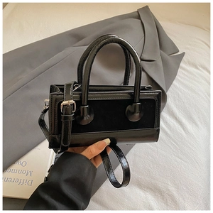 Detail of black crossbody bag with ball ornaments and premium textured stitching
