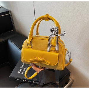 Close-up of yellow leather and suede拼接 bag with bow detail and plaid ribbon handle