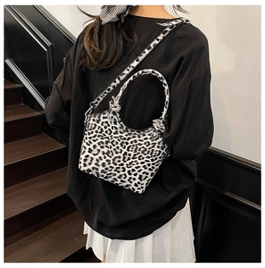 Detailed side view of the stylish leopard print crossbody bucket bag worn by a model