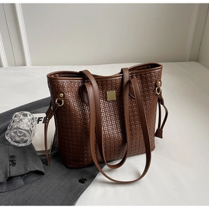 Macro view of woven brown leather tote bag with gold buckle and double handle details