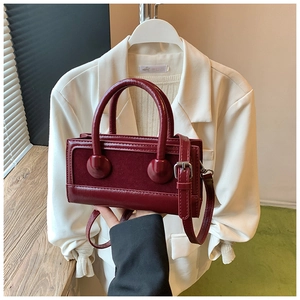 Close-up of deep red leather crossbody bag with mixed smooth and suede textures