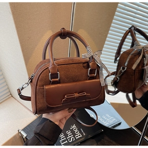 Brown faux suede handbag with bow detail and plaid ribbon shown in a mirror reflection