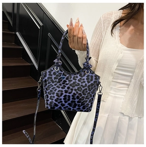 Close-up of blue leopard print handbag featuring glossy patent leather and silver metal rings
