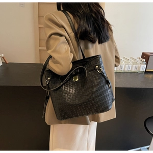 Detail of black woven tote bag with gold metal hardware and textured PU leather finish