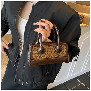 Detailed shot of leopard print mini tote bag with vintage brown leather handles and hardware