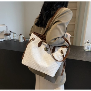Detail of woven tote bag with brown leather trim shown on model for capacity and fit