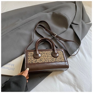Detail of retro small square bag featuring leopard print panel and adjustable brown strap