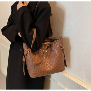 Detail of dark brown woven tote bag showing texture and dual strap carrying style