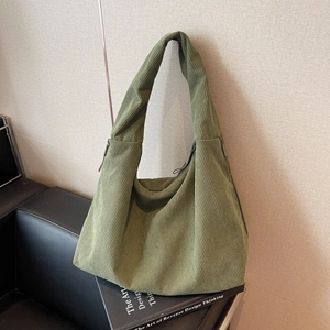 Sac hobo en velours côtelé vert avec fermeture éclair sur un livre noir, style minimaliste