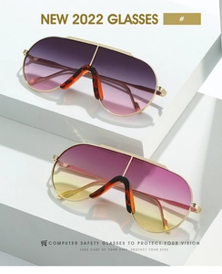 Detail of oversized shield sunglasses with gold metal frames on white geometric steps