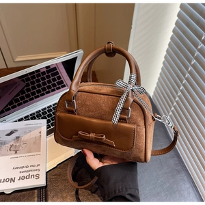 Detail of brown Boston bag with suede stitching, bow pocket and checkered ribbon handle