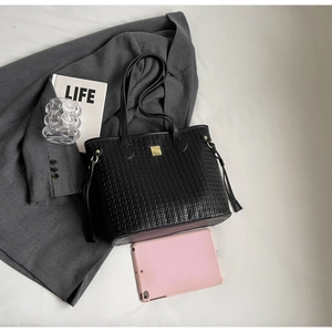 Detailed view of black woven texture tote bag featuring a square gold metal buckle clasp