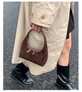 Detail of dark brown suede crescent bag featuring a textured finish and silver dual zippers