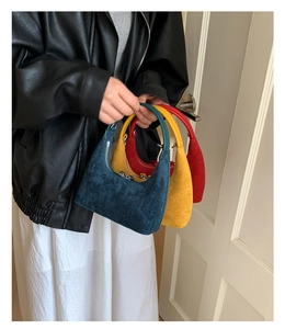 Three elegant crescent bags in navy, yellow, and red suede texture held by a model