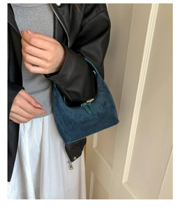 Detail of a dark teal suede crescent handbag with high-quality dual zipper closure