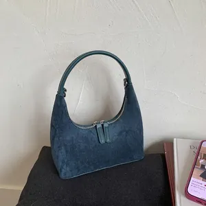 Detailed close-up of teal suede crescent underarm bag with dual zipper and curved handle