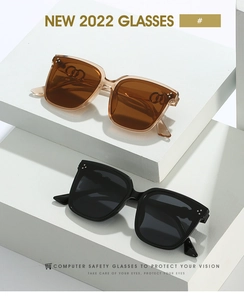 Detail of square oversized sunglasses with amber and black frames on minimalist platforms