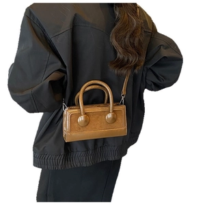 Brown rectangular bucket bag with round handles and crossbody strap on model