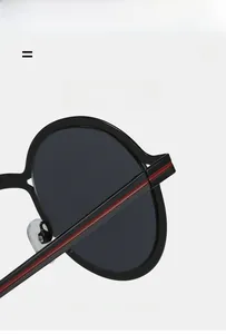 Detail show of lightweight black round sunglasses with red striped temples and elastic frames