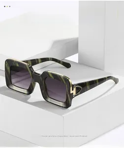 Detail of green marble square frame sunglasses with gold accents and purple gradient lenses