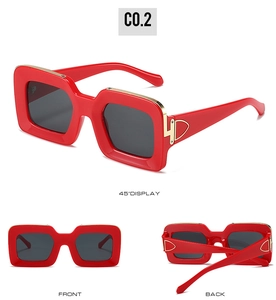 Detail view of red thick frame square sunglasses with gold metal hinge accents