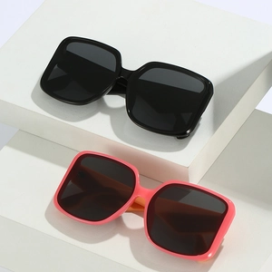 Square oversized sunglasses in black and pink orange on minimalist display stands