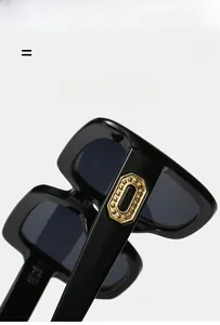 Gros plan de lunettes de soleil carrées noires avec rivets métalliques octogonaux dorés