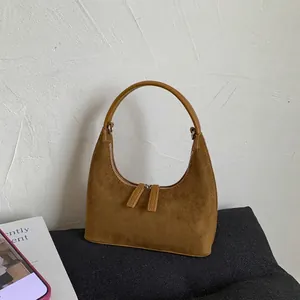 Minimalist brown suede moon bag with dual zipper and a stylish curved top handle