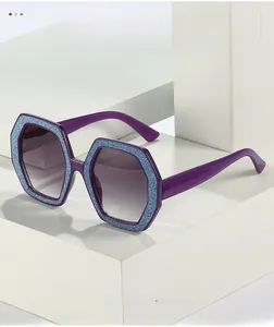 Dettaglio occhiali da sole esagonali con montatura glitterata blu e lenti viola sfumate