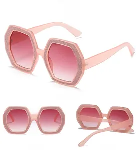 Viste dettagliate di occhiali da sole esagonali con glitter rosa e lenti sfumate chic