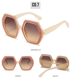 Dettagli di occhiali da sole poligonali color champagne con montatura glitterata rosa