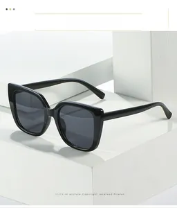 Close-up of stylish black oversized cat-eye sunglasses on a minimalist white stone base