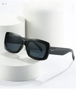 Vue détaillée de lunettes de soleil noires carrées sur un support blanc géométrique
